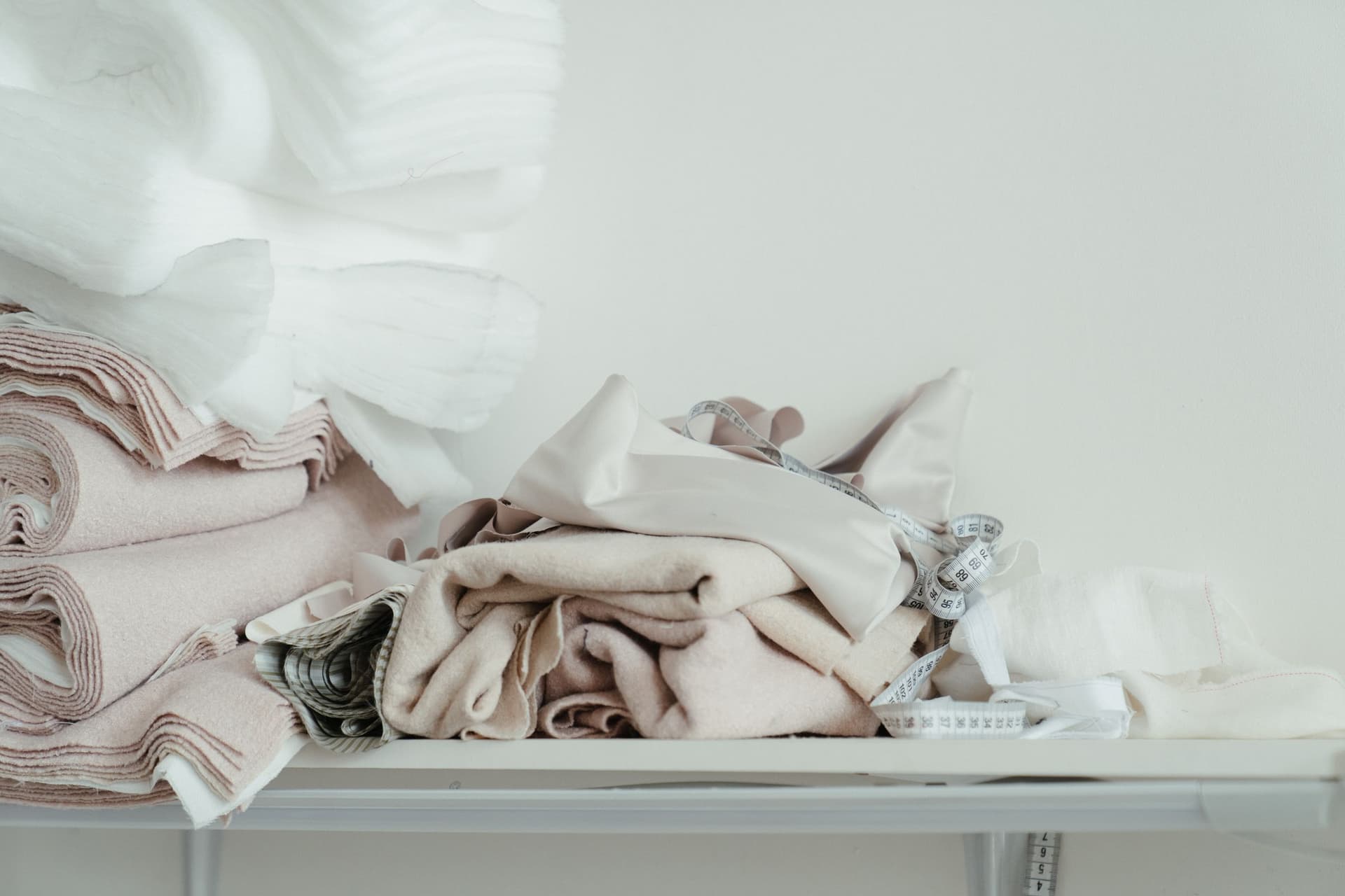 Soft piles of ivory and blush fabric on an atelier table